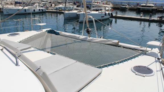 Trampoline and cushioned sun loungers on the deck of Catamaran Ayda1 in the harbor.