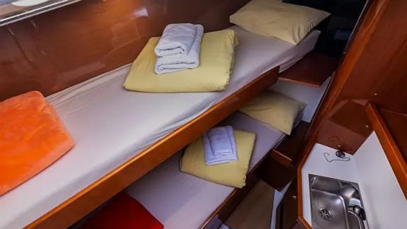 The bunk-bed cabin of the Tourbillon yacht offers a comfortable stay with yellow and orange pillows.