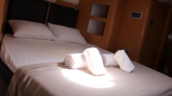 Made-up double bed cabin in Catamaran Ayda1 with folded towels on the bed.