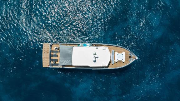The Calm Down yacht gracefully sails on the open blue sea, captured from a bird's-eye view.