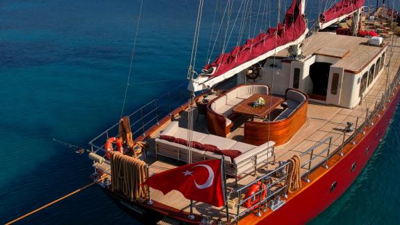 Eine elegante Segelyacht mit rotem Segel, ausgestattet mit gemütlichen Sitzgelegenheiten und einer türkischen Flagge am 