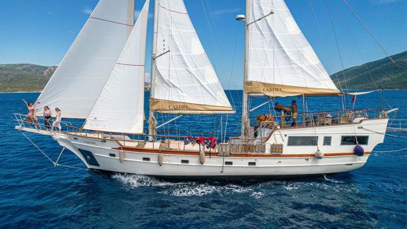 Die 22 Meter Gulet Castiel segelt majestätisch vor der Küste von Bodrum mit glücklichen Gästen an Bord.