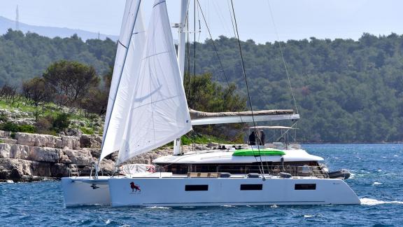 Lagoon 620 Adriatic Lion under sail near rocky Croatian coastline, available for rent with skipper