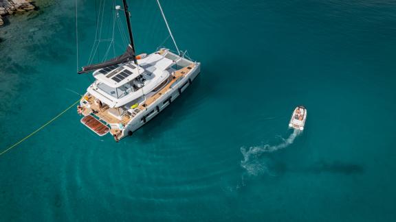 Agenda 55 catamaran is anchored in turquoise waters near Kastela with a tender boat approaching the yacht.
