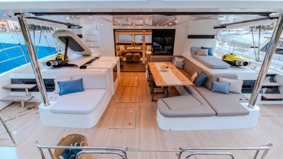 Agenda 55 catamaran features spacious lounge seating and an outdoor dining table on the aft deck.