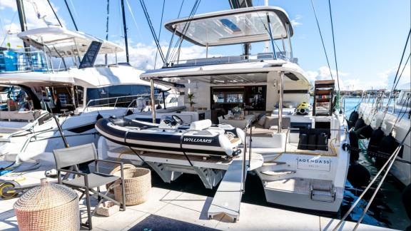 Agenda 55 catamaran features a spacious aft deck with lounge seating and a tender boat at the marina.