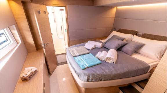 Agenda 55 catamaran features a spacious master cabin with a double bed and private bathroom entrance onboard.
