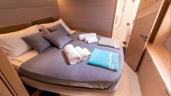 Agenda 55 catamaran features a modern double cabin with comfortable bedding and private bathroom access onboard.