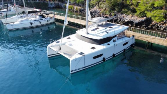 Катамаран Agosto, пришвартованный у причала, демонстрирует элегантный и современный вид на кристально чистой воде.