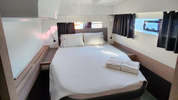 Уютная двухместная каюта катамарана Astrea 42 с просторной кроватью и видом на море из окна.