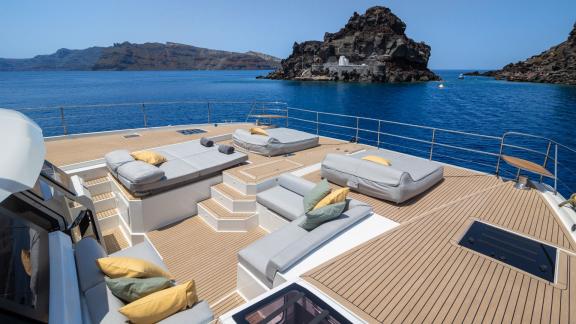 Spacious catamaran sun deck overlooking the sea and rocky island.