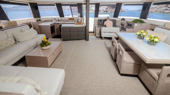 Luxurious salon with dining area and panoramic sea views inside a catamaran.