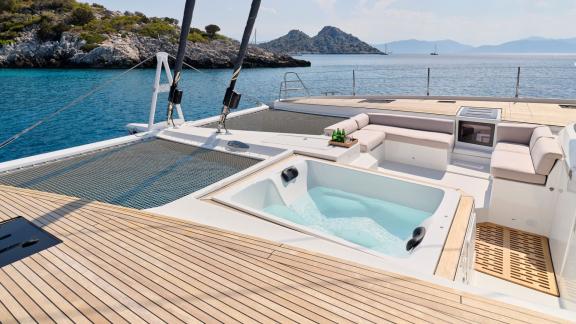 Ein luxuriöser Jacuzzi auf dem Deck des Katamarans Alexandra II, umgeben von klarem Wasser und felsiger Küste.