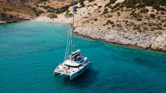 Allure catamaran for rent rests in clear turquoise waters of a quiet cove.
