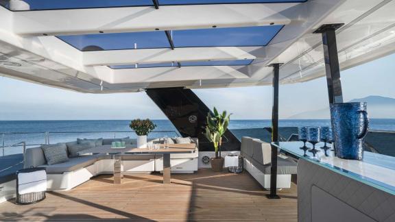 Stylish outdoor area with a lounge and bar on the Catamaran Alteya, offering panoramic views of the sea and mountains.