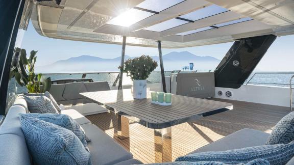 Comfortable lounge area on the Catamaran Alteya, featuring a stylish table and stunning views of the sea and mountains.