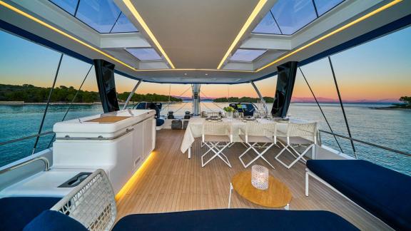 Modern dining area on the flybridge with a stylishly set table and sea view at sunset