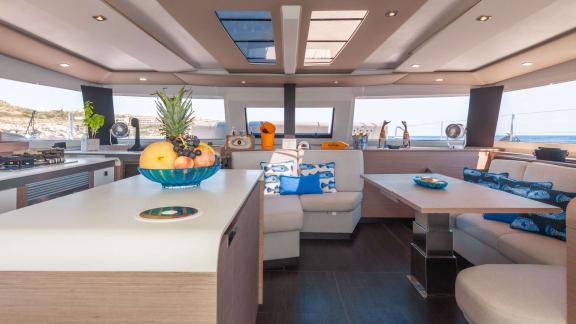 Bright and open living area of a catamaran with a cozy seating corner and modern dining space.