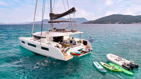 Der Katamaran Andiamo im türkisfarbenen Wasser mit Paddleboards und Beiboot.