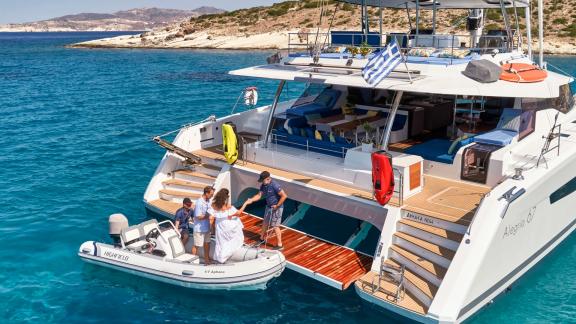 Gäste werden nach einer Bootstour zurück an Bord des Katamaran Aphaea gebracht, der in kristallklarem Wasser vor Anker l