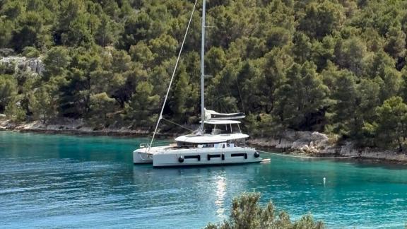 The Artisan catamaran rests peacefully in a turquoise cove near Split, offering a luxury charter escape.