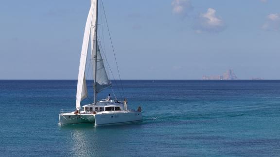 Katamaran Atlantis segelt durch das klare Wasser von Ibiza. Perfekte Wahl für eine wöchentliche Katamaranmiete in Spanie