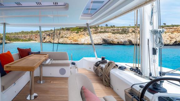 Cozy seating area on the Lagoon 55 catamaran with views of turquoise waters and rocky shores.