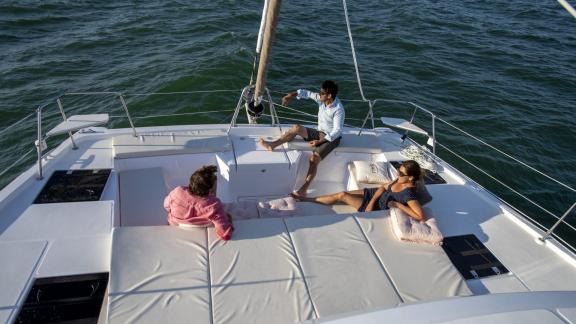 Gäste entspannen sich auf dem Deck des Katamarans Balize und genießen das Meer.