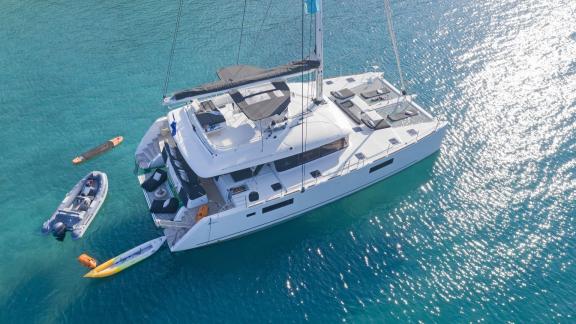 The Lagoon 560 sailing yacht for rent in Athens with a kayak, inflatable boat, and paddleboard on turquoise waters.