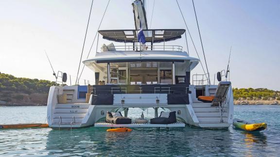 The Lagoon 560 in Athens features a luxurious aft view with a seating area and water toys on calm waters.