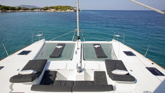 The foredeck of the Lagoon 560 in Athens with comfortable sunbathing areas and nets, perfect for relaxing over turquoise