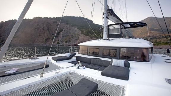 The foredeck of the Lagoon 560 in a secluded bay near Athens, featuring cozy seating areas and nets for relaxation.