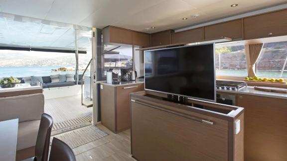 The modern interior of the Lagoon 560 in Athens features a large TV, a well-equipped kitchen, and views of the sea.