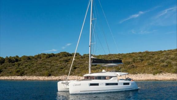 Катамаран Catwalk Lagoon 51 стоит на якоре у зелёного берега и предлагает спокойный отдых.