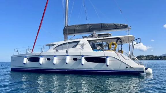 The catamaran Cecilia is peacefully anchored in blue waters, seen from a side profile.