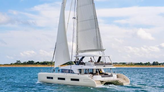 The Catamaran Daiquiri sails peacefully along the scenic coast of Athens, Greece, under clear skies and calm waters.