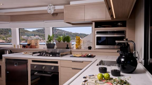 The kitchen of Dream catamaran offers a spacious counter, modern appliances and windows with sea views.