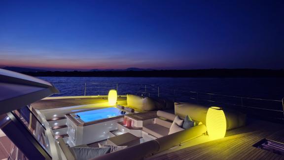 Yacht Elly bei Dämmerung mit beleuchtetem Whirlpool und gemütlicher Atmosphäre auf dem Deck.