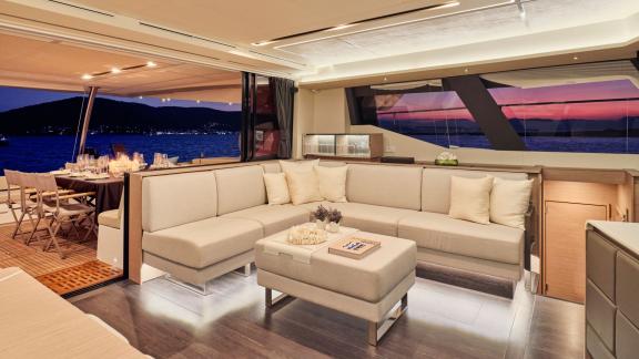 Eleganter Salon der Yacht Elly mit Blick auf den Essbereich und das Meer bei Sonnenuntergang.