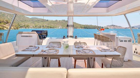 Elegantly set outdoor dining table on the Genny catamaran, with views of the sea and surrounding hills.