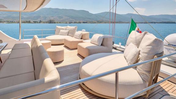 Komfortabler Lounge-Bereich mit großzügigen Sitzmöbeln auf dem Deck des Katamarans Genny, mit malerischer Aussicht.