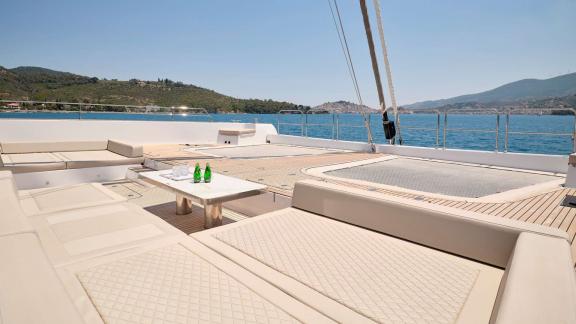 Comfortable lounge area with sunbeds on the deck of the Genny catamaran, overlooking calm seas.