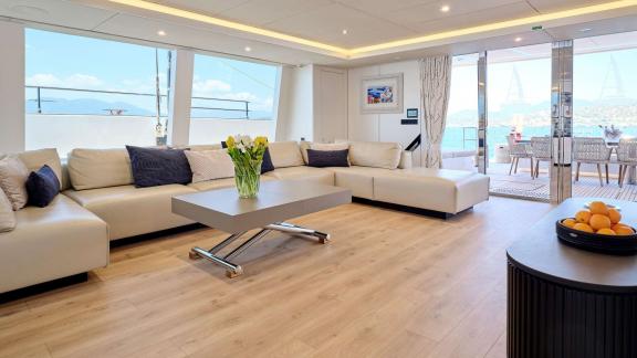 Stylishly furnished salon with large sofas in the Genny catamaran, featuring access to the terrace and sea views.