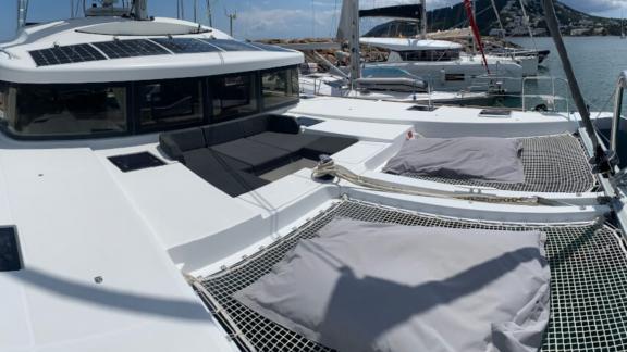 Sonnendeck mit Liegeflächen und Sitzgelegenheiten auf einem modernen Katamaran im Hafen.