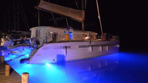 Katamaran Grace II, mavi su altı aydınlatmasıyla limanda gece parlıyor, Türkiye'de bareboat charter için ideal.