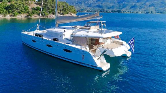 The catamaran High Five is seen at sea from the rear profile, featuring a spacious aft deck.