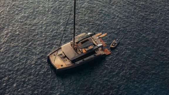 Der Katamaran Honeymoon liegt mit Beiboot und Wasserspielzeug auf offener See vor Anker.