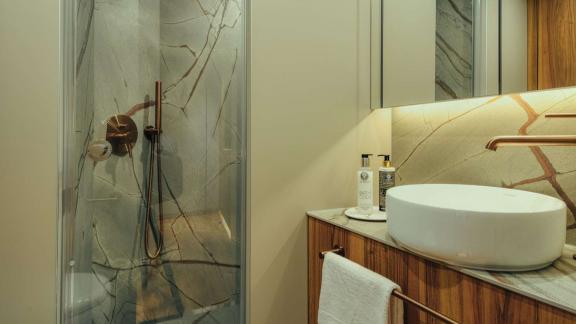 Die Dusche auf dem Katamaran Honeymoon ist mit modernen Armaturen und Steindekor gestaltet.