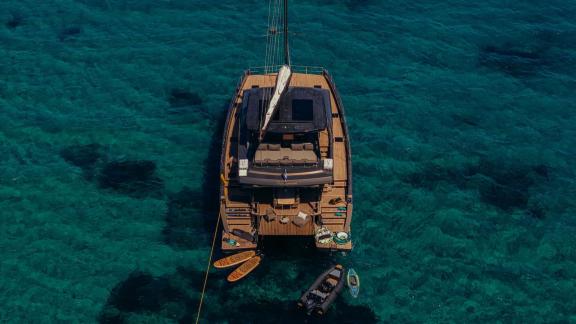 Der Katamaran Honeymoon liegt vor Lavrion vor Anker, mit Paddleboards und Wasserspielzeug am Heckdeck.