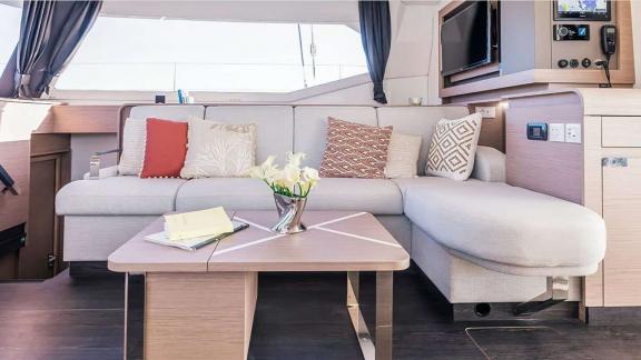 The catamaran Kebisiks features a soft sofa, table, and sea-view corner near Athens.